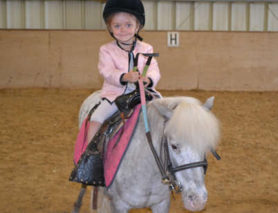 photo d'une petite fille de 3 ou 4 ans sur un poney blanc